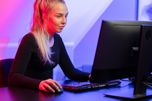 Focused Blonde Gamer Girl Playing Online Video Game on Her Personal Computer.