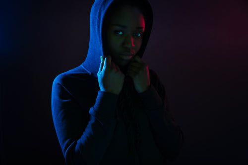 Dark colorful studio portrait of a cool black woman wearing hoodie