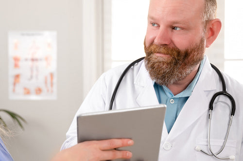 Doctors discussing report about a patient at tablet computer in hospital