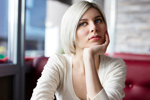 Pensive and thoughtful young woman at cafe