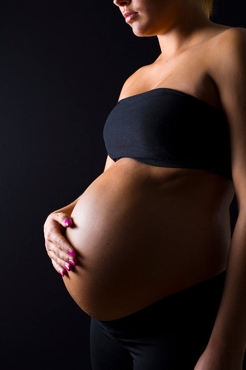 Pregnant woman with her hand on the bare belly