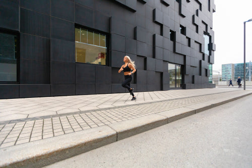 Beautiful fast running woman wearing sports top in modern city environment