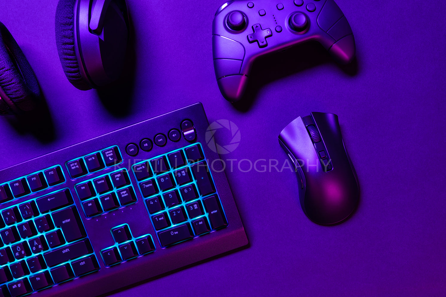 Top view of illuminated gaming gadgets on purple desk