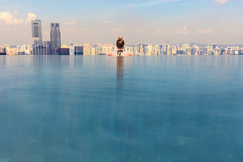 Woman Looking At Cityscape While Relaxing In Infinity Pool