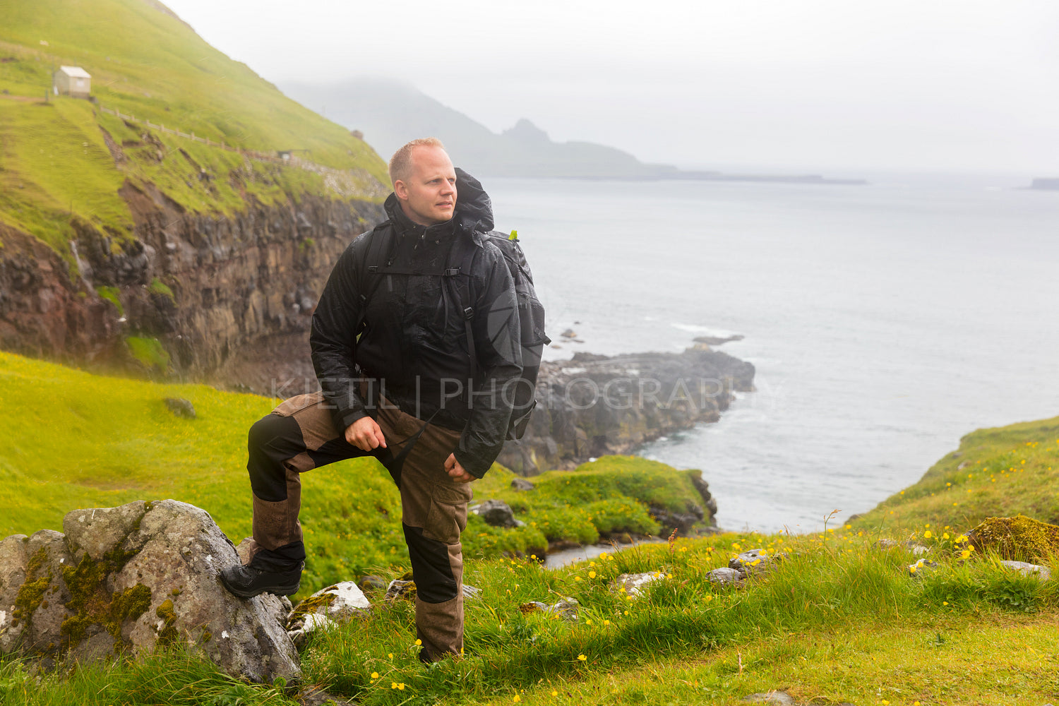 Hiker Standing in the rain On Mountain at Faroe Island With Sea In Background