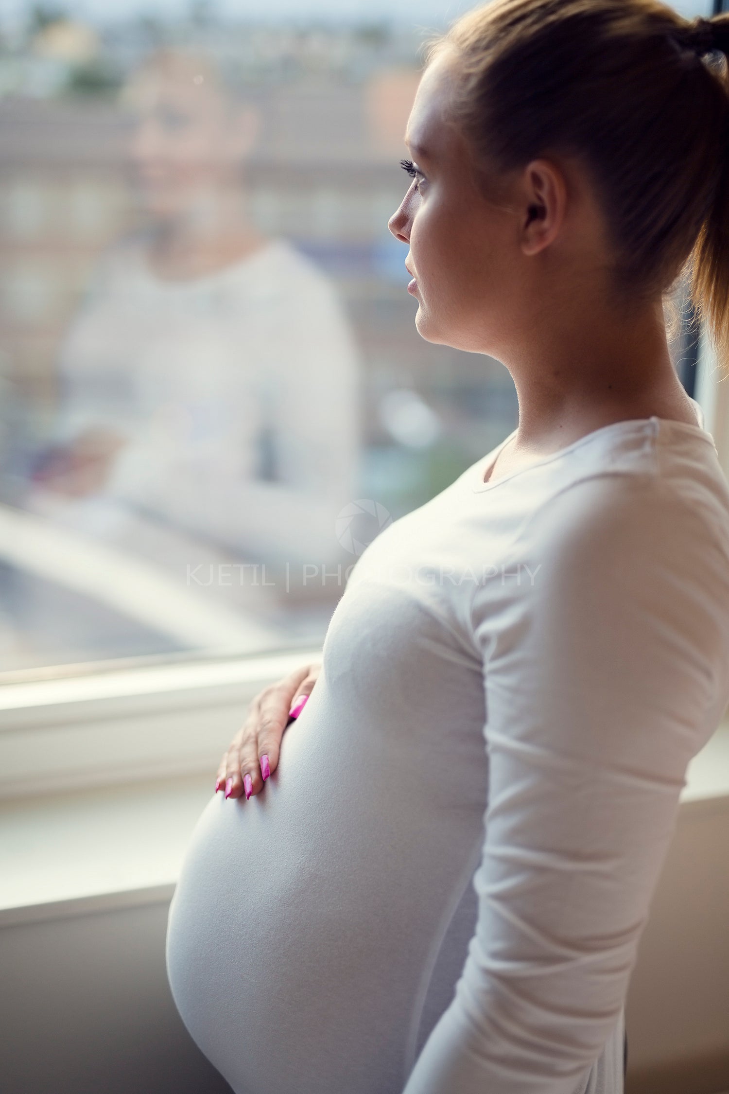 Young thoughtful pregnant woman looking out the window