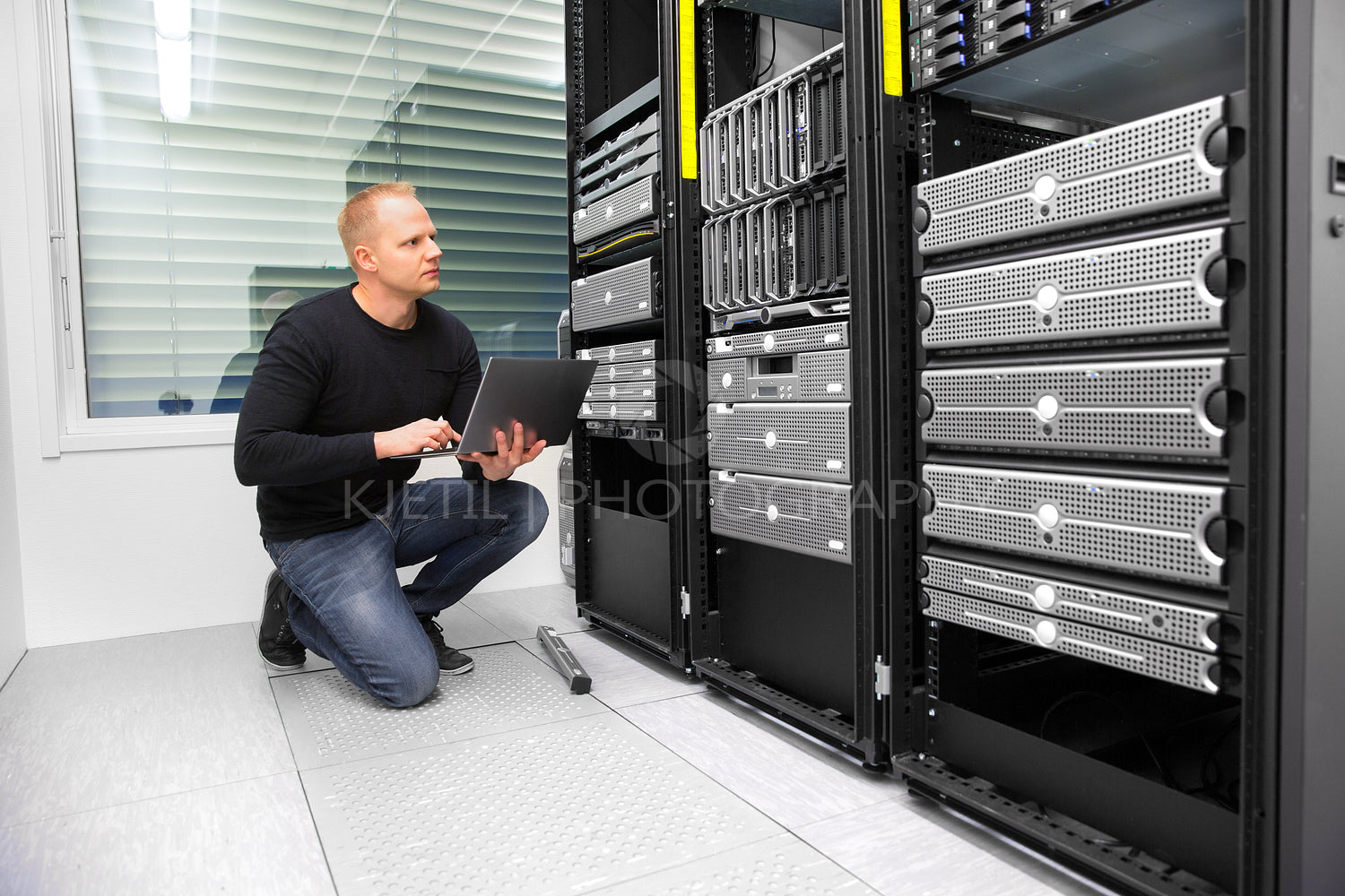 Consultant Using Laptop While Monitoring Servers In Datacenter