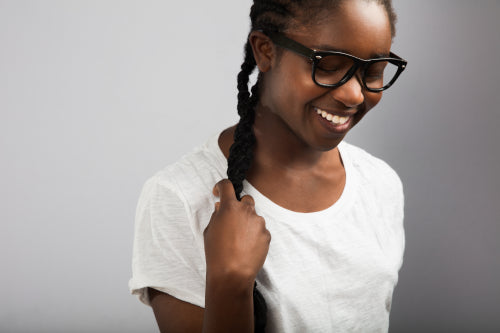 Woman With Braided Hair Wearing Eyeglasses Over Gray Background