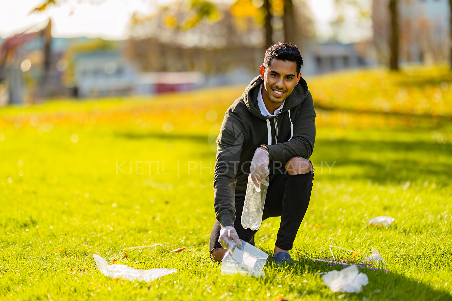 Smiling and committed volunteer cleaning garbage on grass in nature
