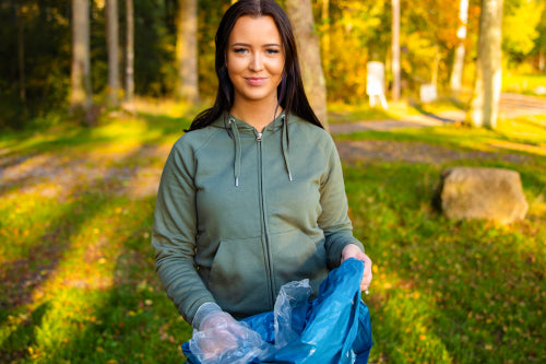 Young smiling female volunteer holding garbage bag at park