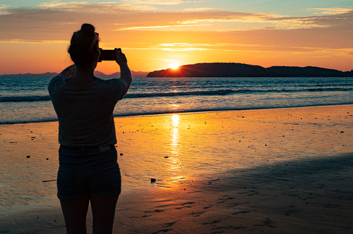 Silhouette Female Tourist Photographing Sea At Beach During Suns