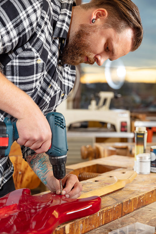 Portrait of craftsman working in workshop with guitar