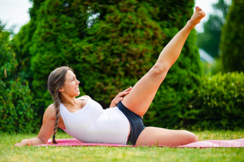 Expectant Woman Doing Side Reclining Leg Lift In Park
