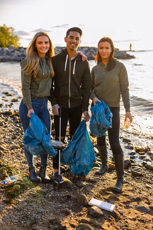 Smiling volunteers friends holding garbage bag at beach