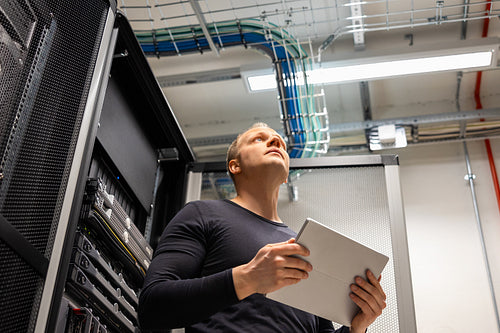 Male IT Professional Holding Digital Tablet Planning Changes in Datacenter