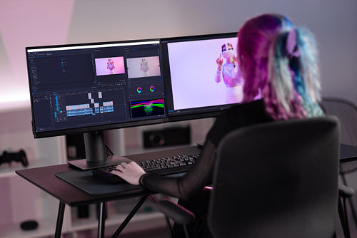 Professional female film editor editing video on his personal computer with two displays in modern video studio