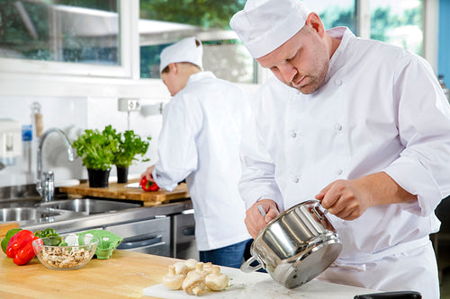 Professional chefs makes food dishes in large kitchen