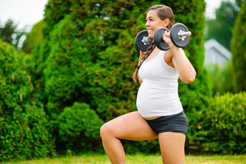 Pregnant Woman Doing Kneeling Lunges With Dumbbells In Park