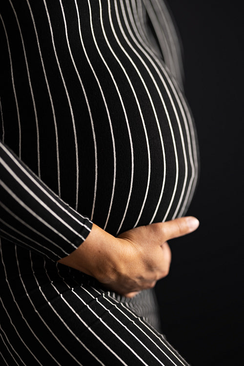 Pregnant Woman in Striped Dress Touching Her Belly