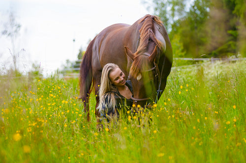 Beautiful woman feeding her arabian horse in the field