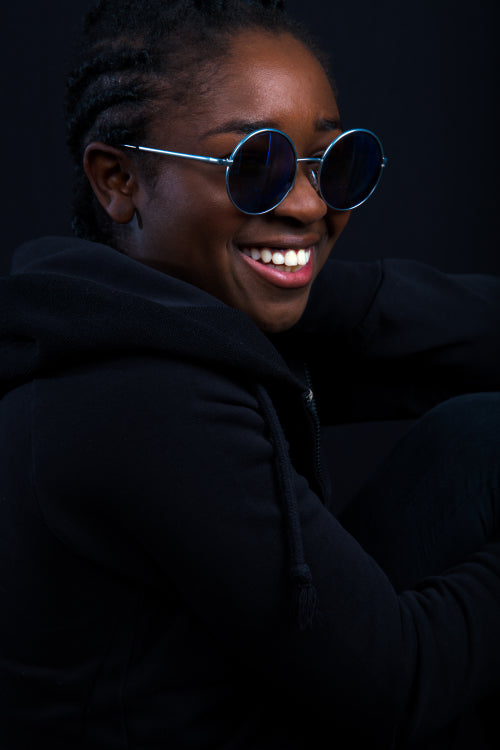 Woman Wearing Sunglasses While Smiling Over Black Background