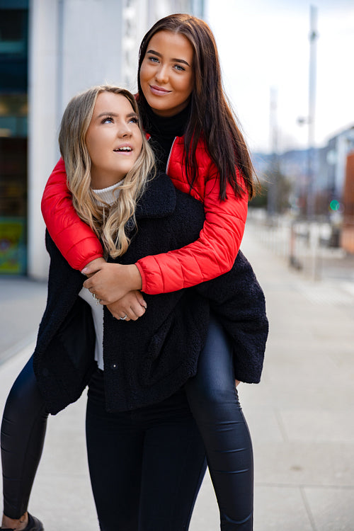Smiling Close Female Friends Having Fun and Piggybacking In City