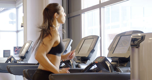 Fit woman in workout clothes running on treadmill machine in fitness gym