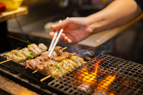 Vendor preparing meat on barbecue grill in Japan