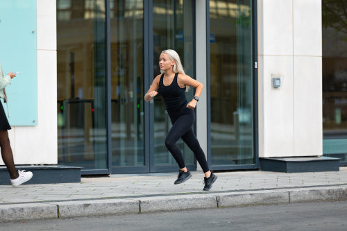 Side view of sporty woman running fast in minimalist urban environment
