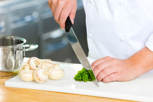Close-up of professional chef cutting parley and mushrooms