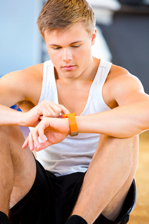 Man Using Smart Watch While Sitting In Gym