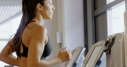 Close-up of fit woman in running on treadmill machine in fitness gym