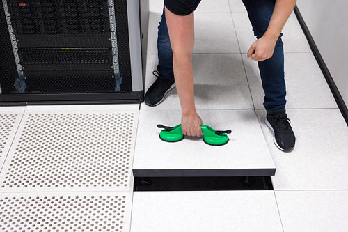 IT Engineer Pulling Floor Tile Using Suction Cups In Datacenter