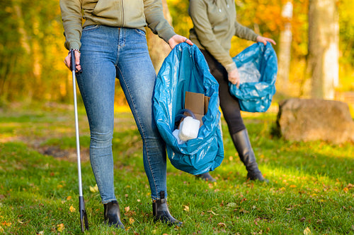 Female volunteers picking up garbage on grass
