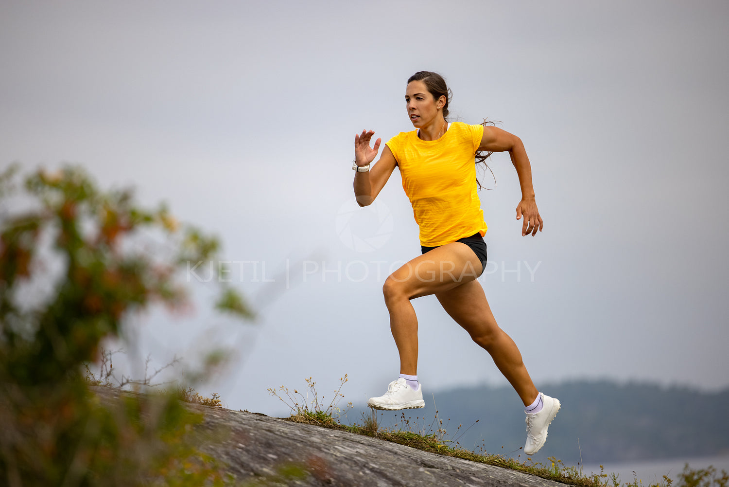 Focused fitness woman doing high-intensity running on mountainside by the sea