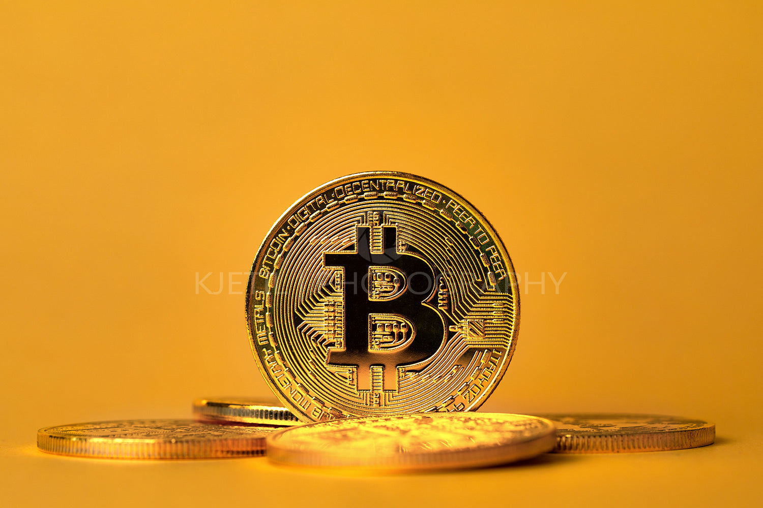 Closeup of standing gold bitcoin on yellow backgound