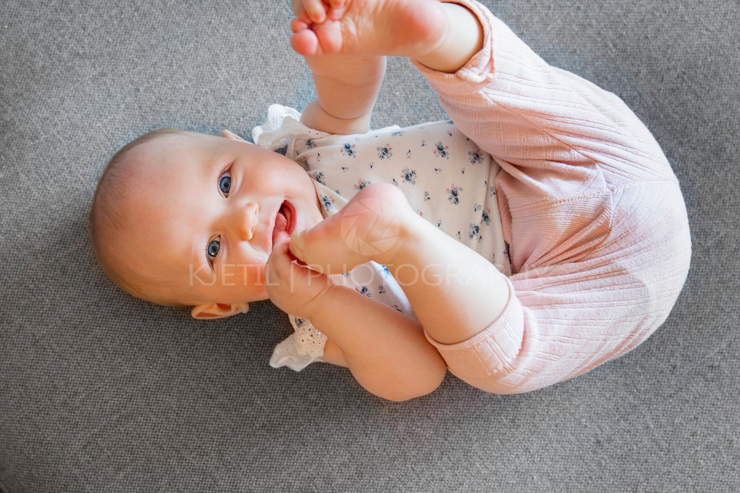 Cute baby girl with blue eyes playing on the sofa