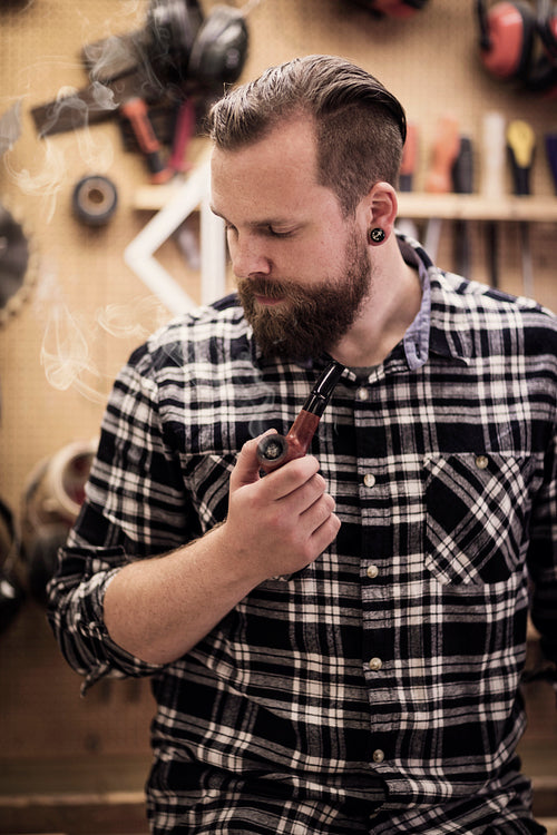 Portrait of a man smoking pipe in wood workshop