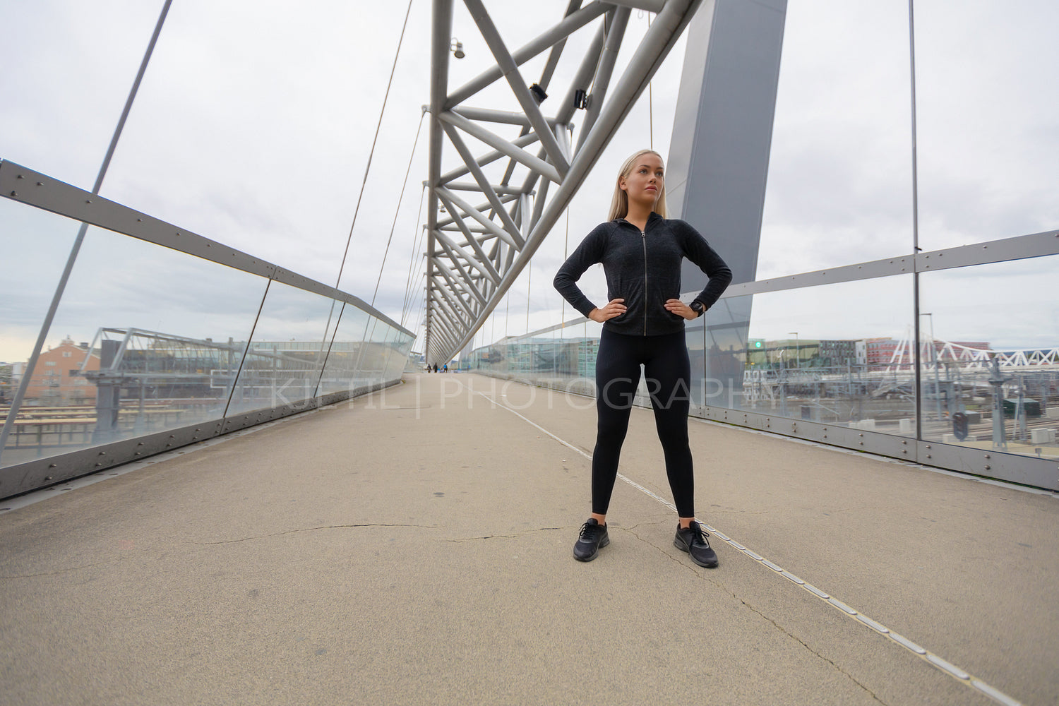 Confident Woman with Hands on the Hips in Workout Outfit Standing on Bridge