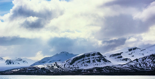Dramatic clouds over snowy mountains in the arctic
