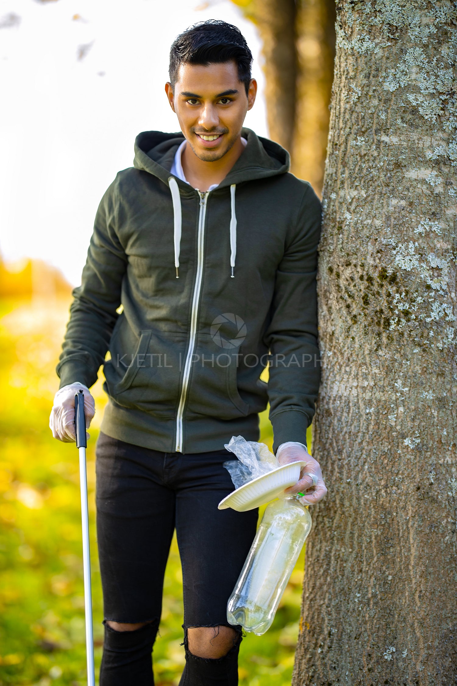 Smiling environmental protection volunteer holding garbage and mechanical grabber