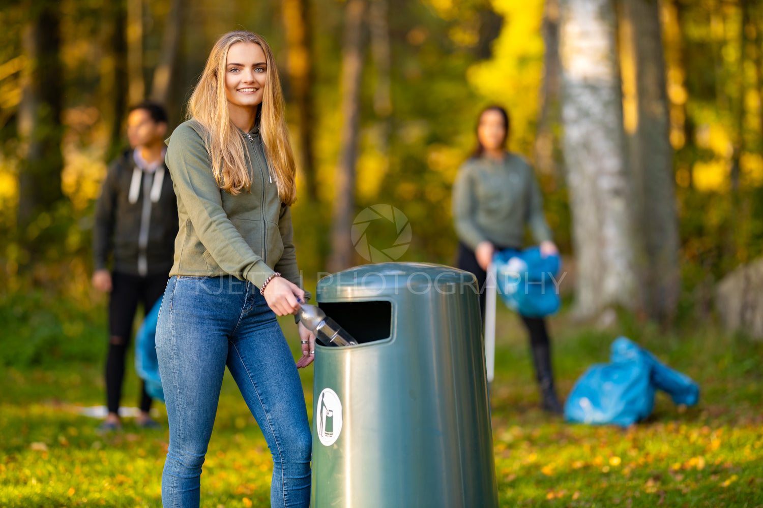 Smiling young woman putting bottle in garbage bin