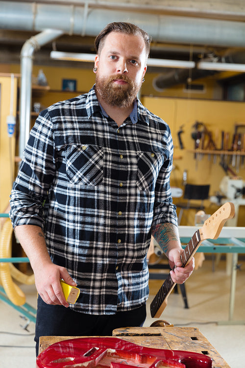 Carpenter work on a wooden guitar neck in workshop