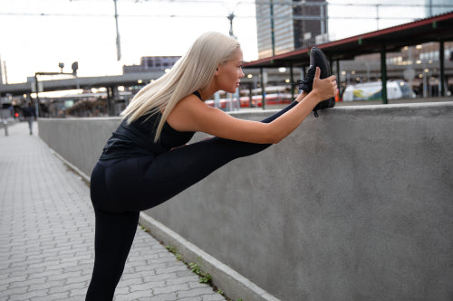 Pretty Woman Doing Stretching Exercise At Sidewalk Railing