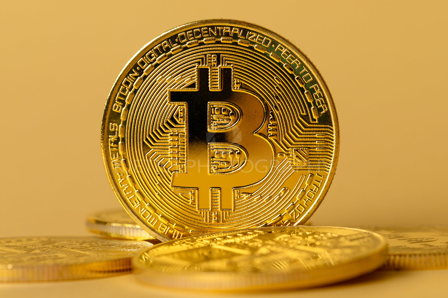 Closeup of gold bitcoin on yellow backgound