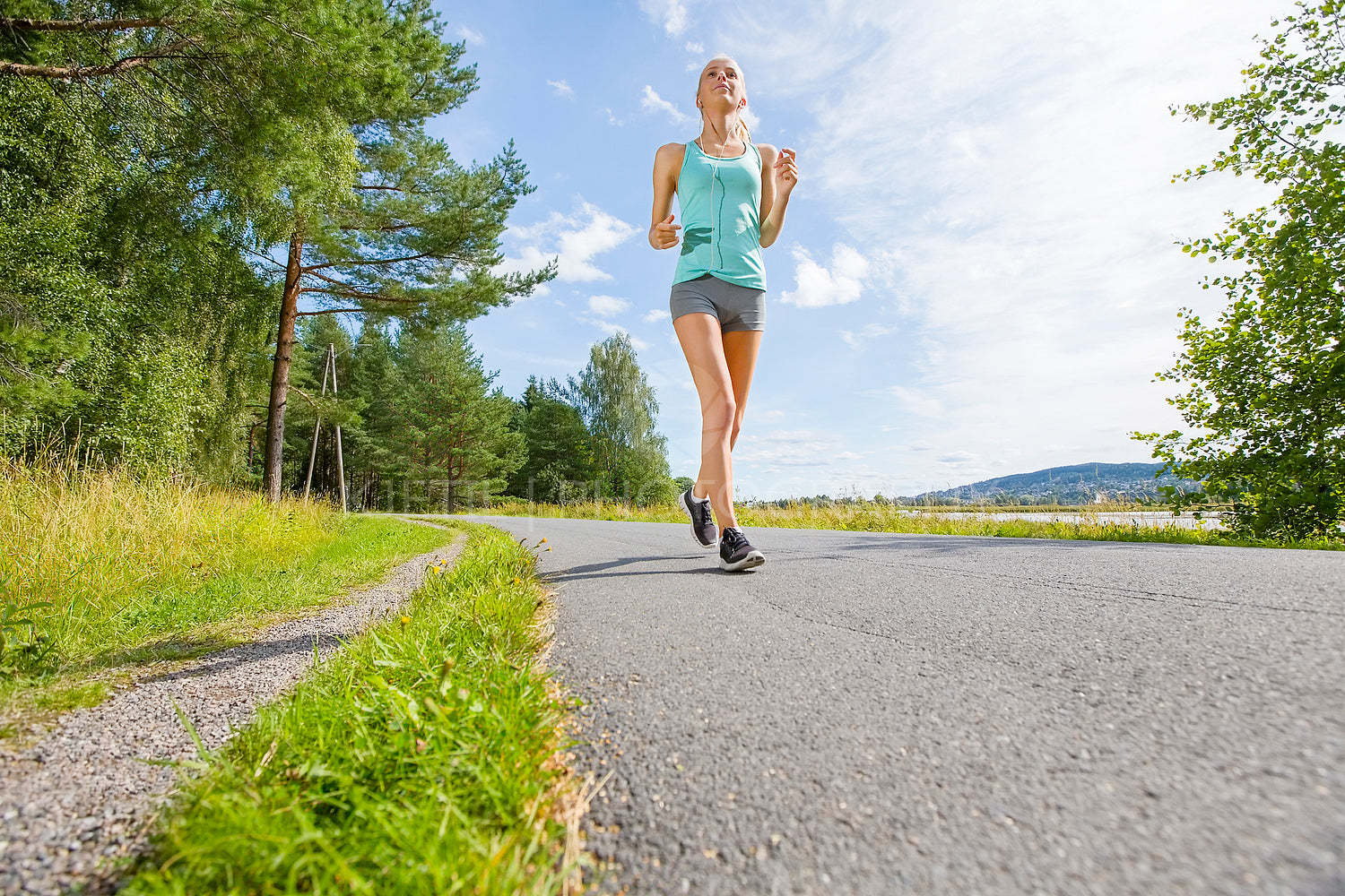 Smiling young woman trains on a road in the forest