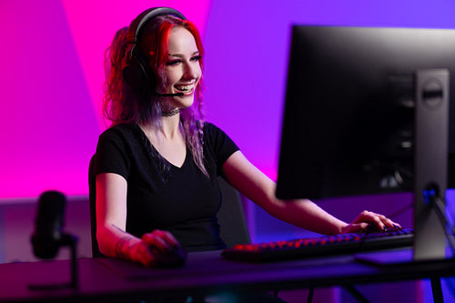 Beautiful and natural smiling esport gamer girl live streaming and plays online video game on computer