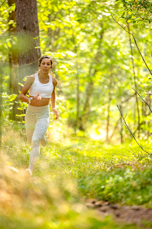 Fit Woman Running In Woodland During Endurance Training