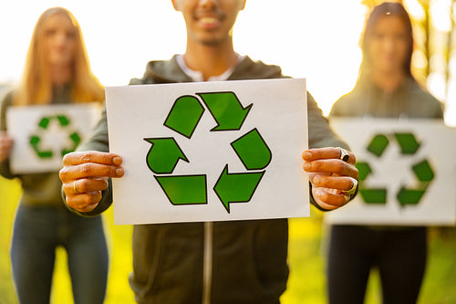 Man holding placard with recycling symbol with his enviromental team at park