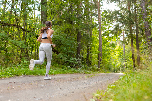 Woman Running In Woodland During Outdoor Workout